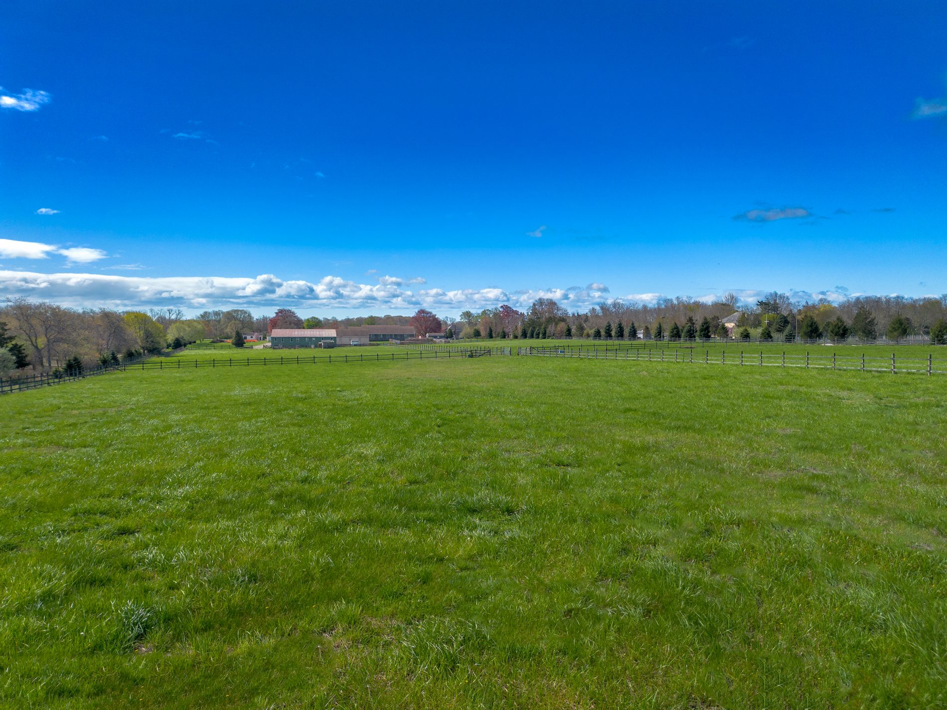 Wide open pasture under a broad sky with a barn in the distance
